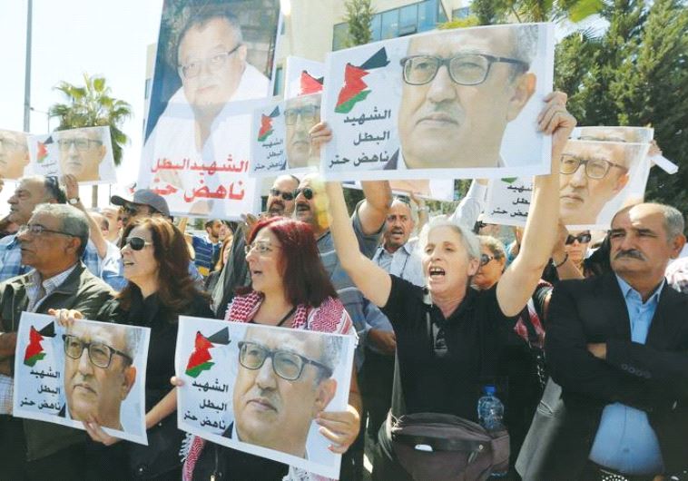RELATIVES AND ACTIVISTS hold pictures of assassinated Jordanian Christian writer Nahed Hattar yesterday in a protest outside the Prime Minister’s Office in Amman, Jordan.