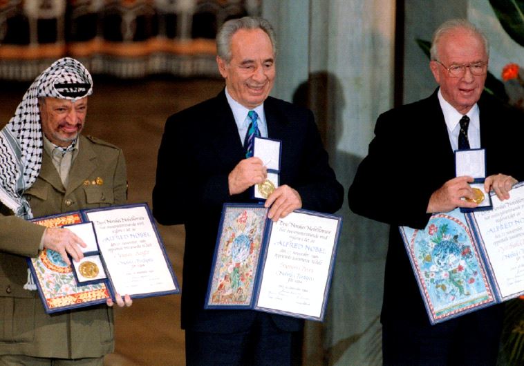 Former PLO chairman Yasser Arafat, then foreign minister Shimon Peres and then prime minister Yitzhak Rabin (from L to R) show their shared Nobel Peace Prize awards to the audience in Oslo in this December 10, 1994 file photo