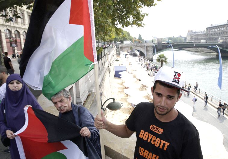 A man wearing a T-shirt of the BDS movement holds a Palestinian flag during a protest against the ‘Tel-Aviv sur Seine’ beach attraction in central Paris last summer