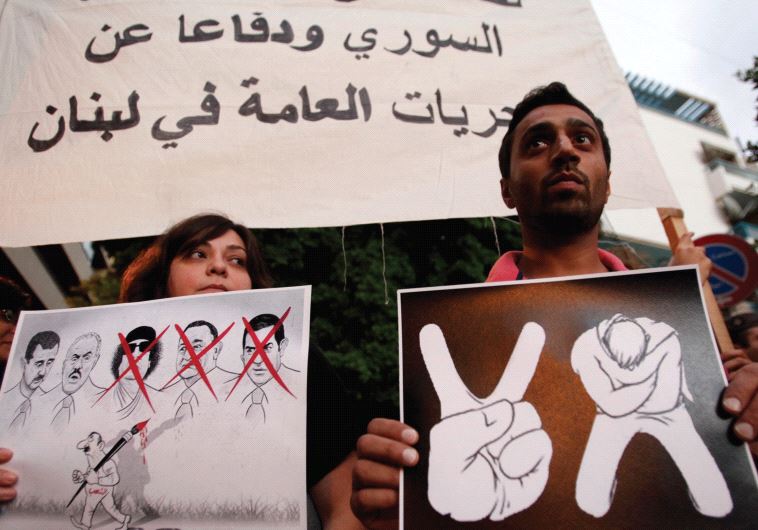 LEBANESE HOLD posters at a protest in front of the Arab League headquarters, in Beirut in 2011. The Syrian regime is still in power today