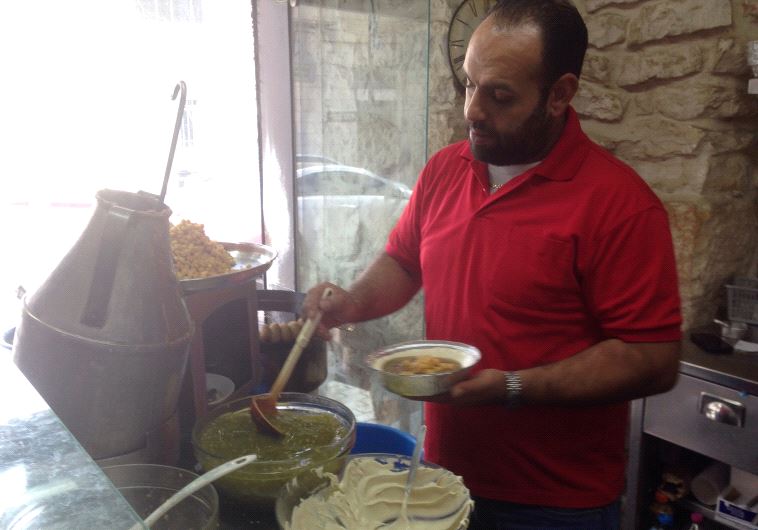 An Employee of Bandali prepares hummus 