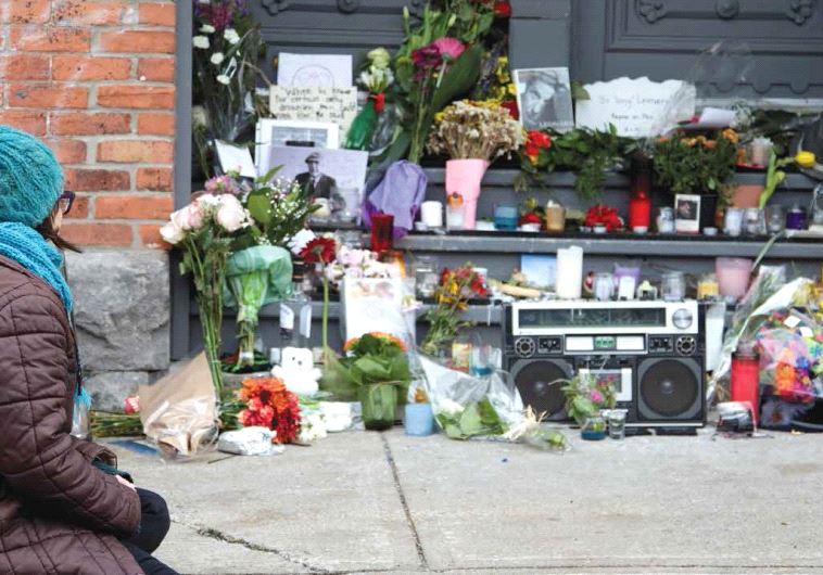 A mourner sits by the steps of the home owned by Canadian singer-songwriter Leonard Cohen in Montreal on November 11