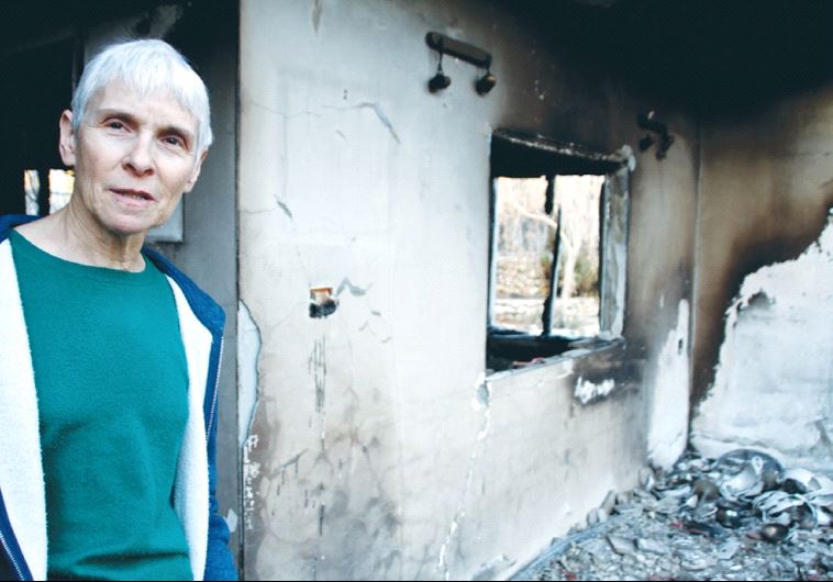 DR. AMY ROSENBLUH stands in the doorway of her fire-gutted home in the settlement of Halamish yesterday. 
