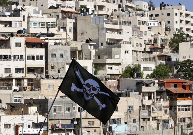 Protesters against Jewish settlement activity in the Silwan neighbourhood, outside the old city in Jerusalem hold a skull and bones flag