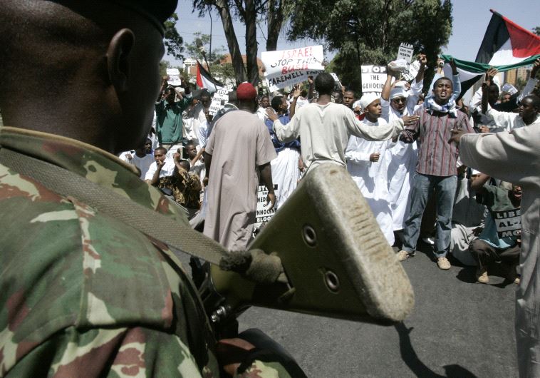 An anti-riot policeman blocks Muslim protesters from marching to the Israeli embassy during a demonstration in Nairobi.