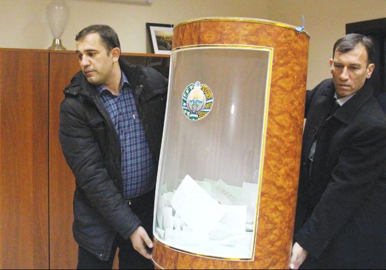 MEMBERS OF a local electoral commission carry a ballot box after the presidential election in Tashkent, Uzbekistan, yesterday.