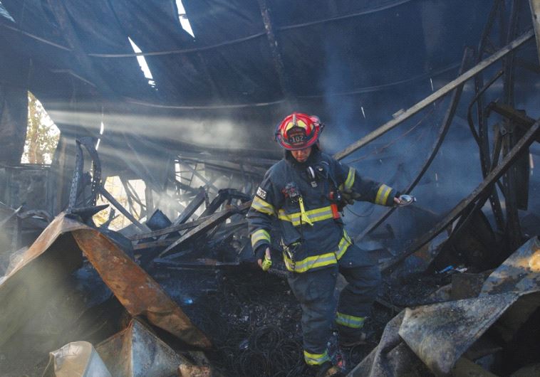 A FIREFIGHTER WALKS inside a building destroyed by fire in Beit Meir, near Jerusalem, in November