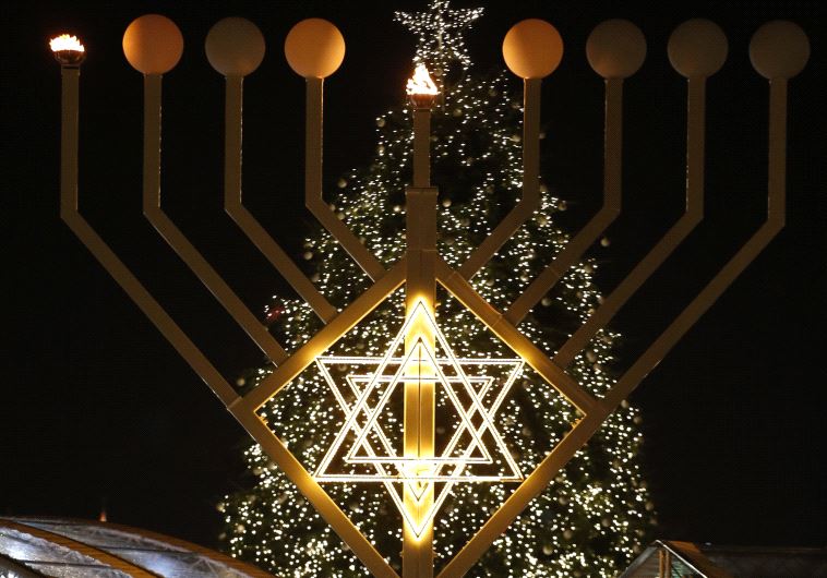A giant menorah stands in front of a Christmas tree at the Brandenburg gate to celebrate Hanukkah in Berlin December 16, 2014