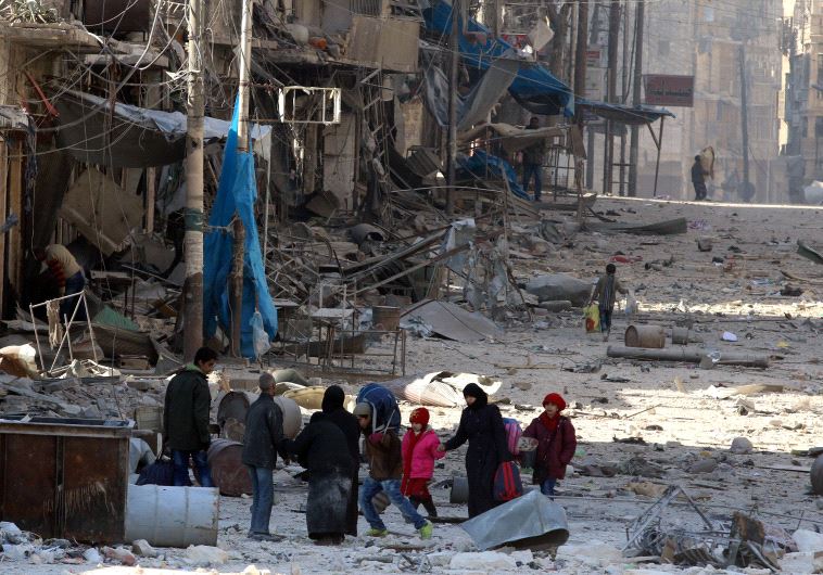 Syrians walk over rubble of damaged buildings in Aleppo, November 28, 2016