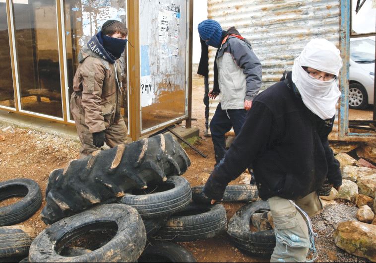 ISRAELI YOUTHS construct a barrier using tires in the settler outpost of Amona yesterday. 
