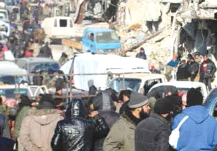 Rebel fighters and civilians wait near damaged buildings to be evacuated from a rebel-held sector of eastern Aleppo, this week