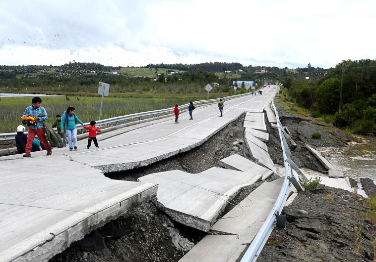 People inspect damage caused on highway 5 south on Chiloe Island off the Pacific coast of southern Chile, by a 7.7-magnitude earthquake on December 25, 2016