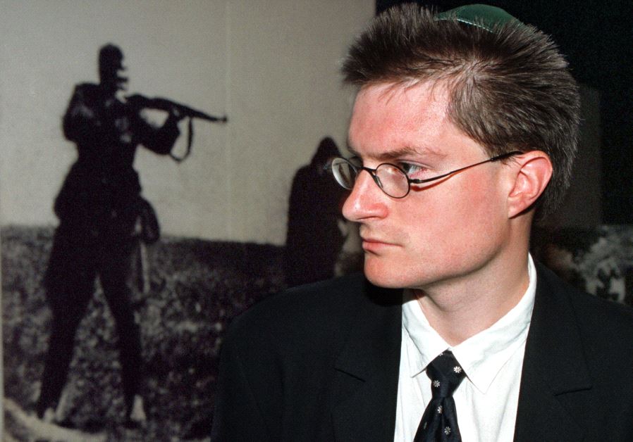 Christoph Meili, a former Swiss bank security guard, wears a yamulka as he passes a photo mural of a Nazi soldier executing a Jewish woman during a tour of the Yad Vashem Holocaust Museum in 1997.