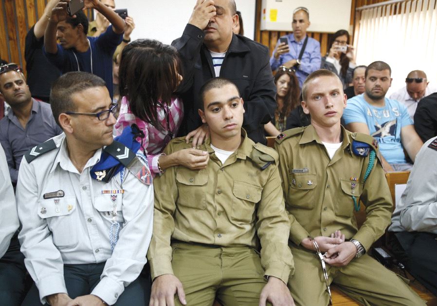 THE FATHER of convicted Sgt. Elor Azaria (center) prays behind him in a military court during a remand hearing for his case last March