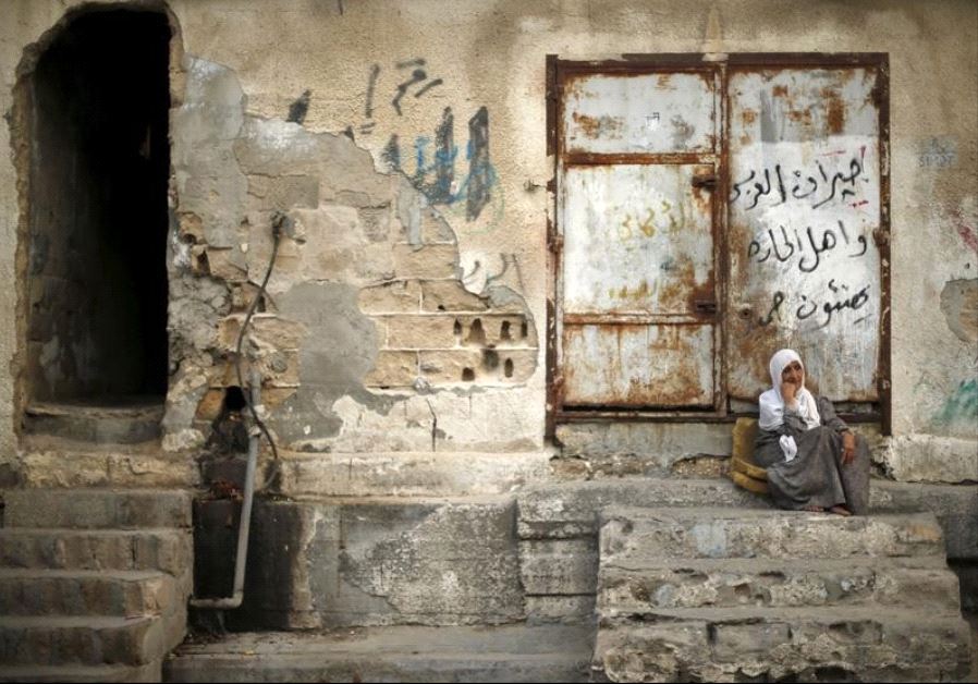 A Palestinian woman sits outside her house as she escapes the heat during a power cut at Shatti (beach) refugee camp in Gaza City September 15, 2015. 