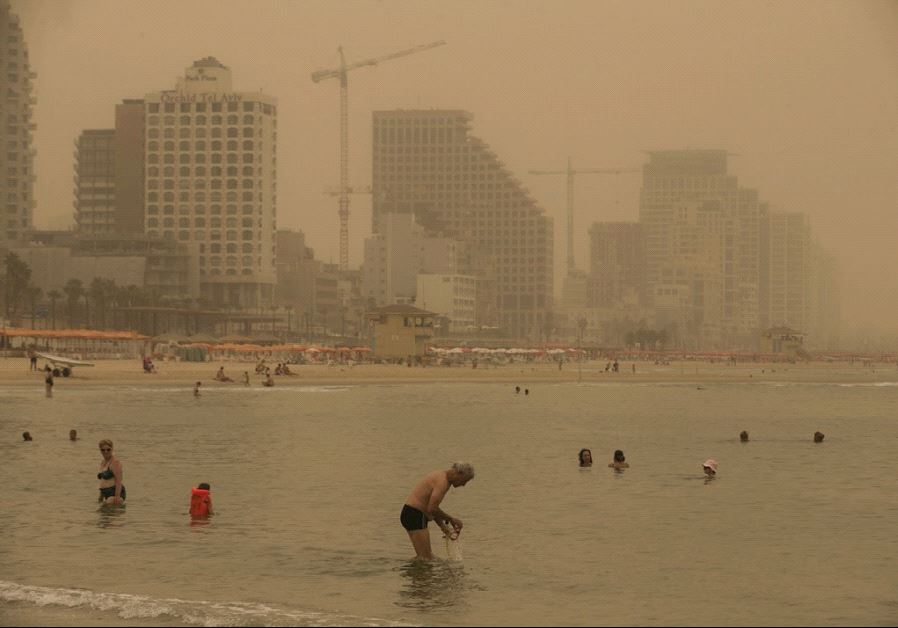 BEACHGOERS in Tel Aviv ignore the August 2015 sand and dust storm to take a swim. (