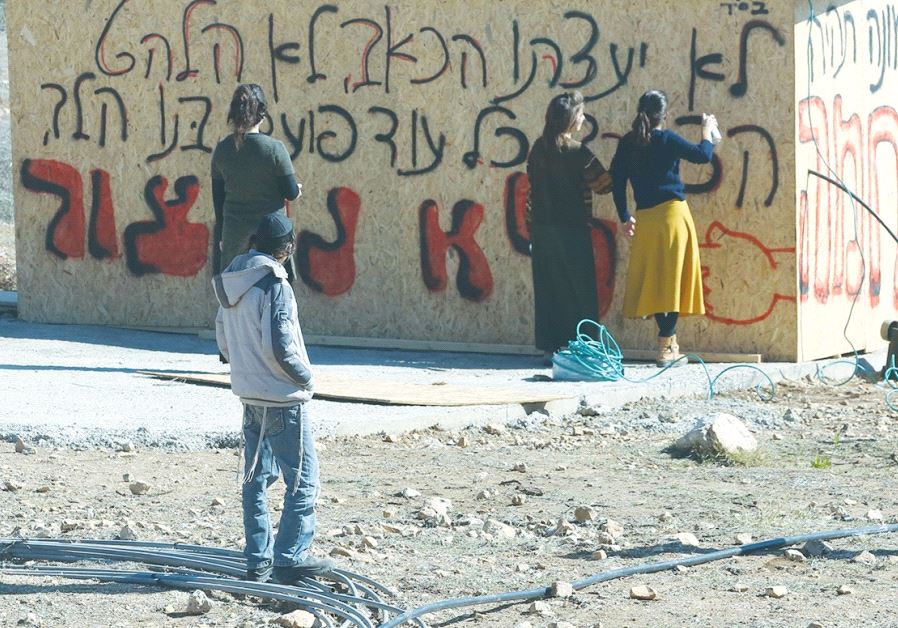 RESIDENTS GATHER by a shed in the Amona outpost in Samaria last month.
