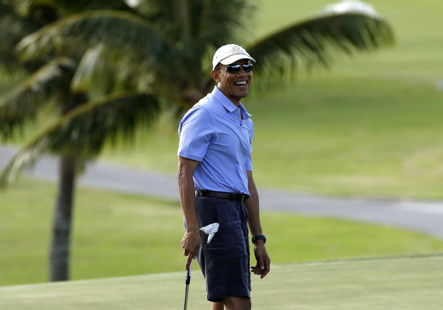 Barack Obama smiles as he plays golf in Hawaii