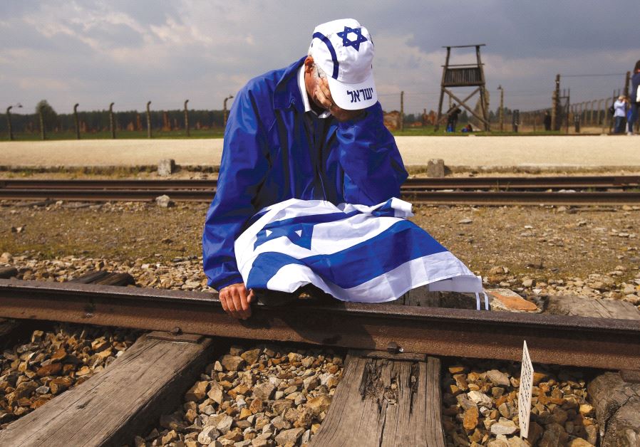 A man sits on the railway tracks in the former Nazi death camp of Auschwitz-Birkenau as thousands of people, mostly youth from all over the world, gather for the annual March of the Living t
