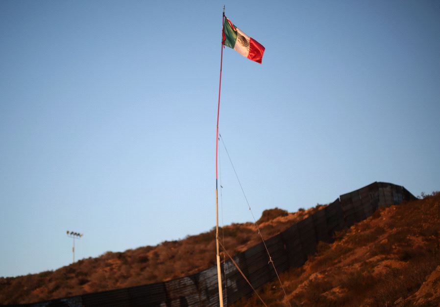 A Mexican flag is seen next to a section of the wall separating Mexico and the United States, in Tijuana, Mexico, October 6, 2016