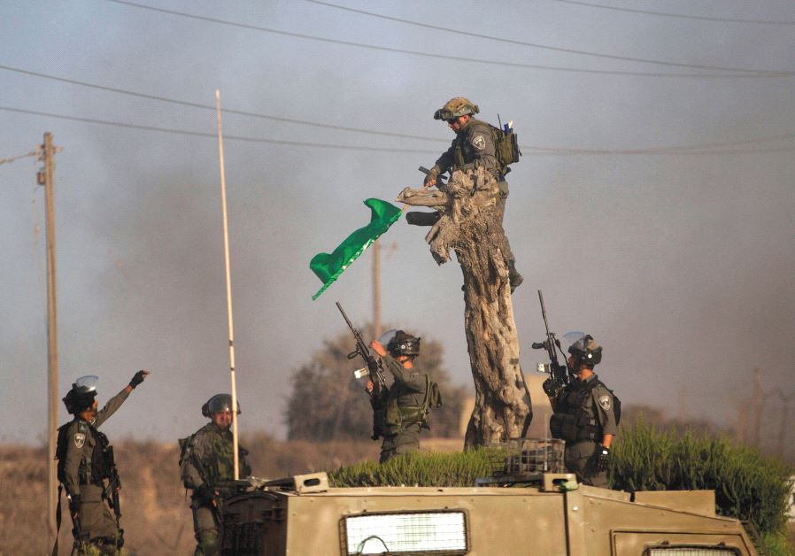 AN ISRAELI border policeman removes a Hamas flag during clashes with Palestinian protesters in the West Bank town of Al-Ram, near Jerusalem