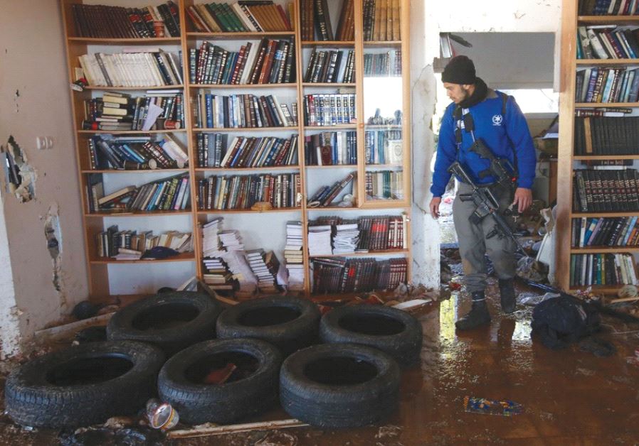 A SECURITY OFFICER surveys the inside of a synagogue in Amona yesterday after the youths who barricaded themselves inside were removed.