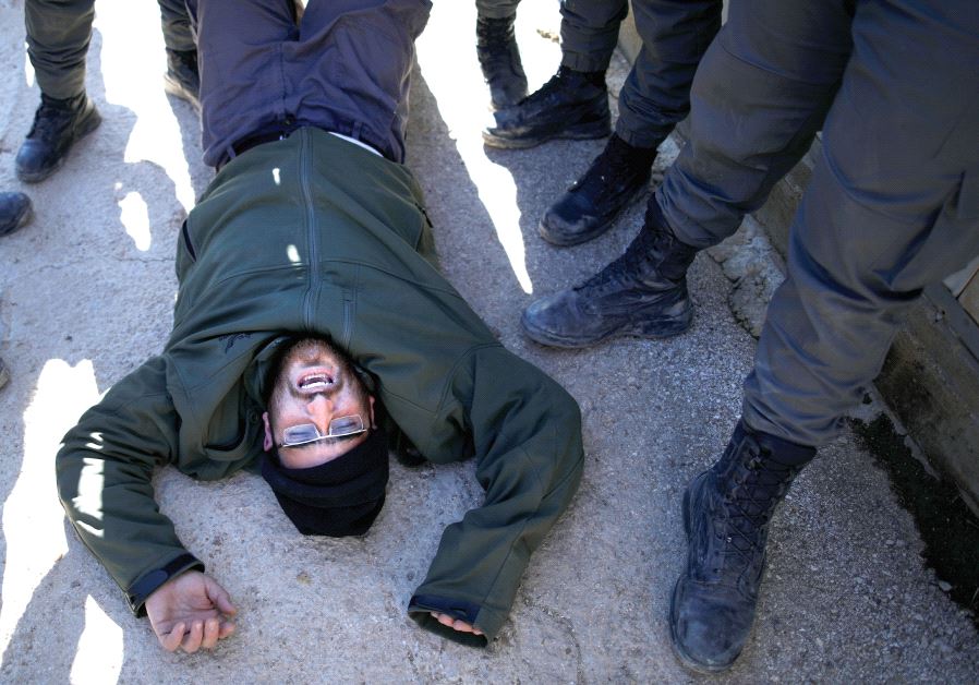 Policemen remove a pro-settlement activist during the second day of an operation to evict settlers from the illegal outpost of Amona in the West Bank, on February 2