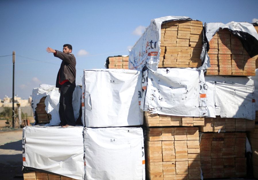 A Palestinian man gestures as he stands atop lumber brought in via Egypt, in Rafah in the southern Gaza Strip. 