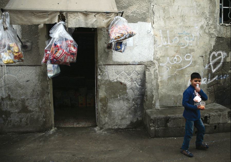 A boy carries goods outside a grocery shop in the rebel-held besieged city of Douma, in the eastern Damascus suburb of Ghouta, this week