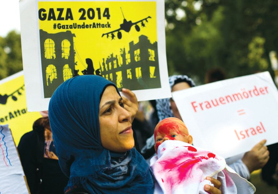 People hold placards during an anti-Israel protest in central Berlin in July 2014. The placard reads ‘Women murderers = Israel.’