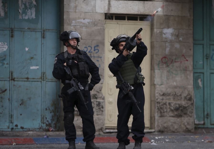 An Israeli border police officer fires a tear gas canister during clashes with Palestinian protesters in the West Bank city of Hebron November 5, 2015.