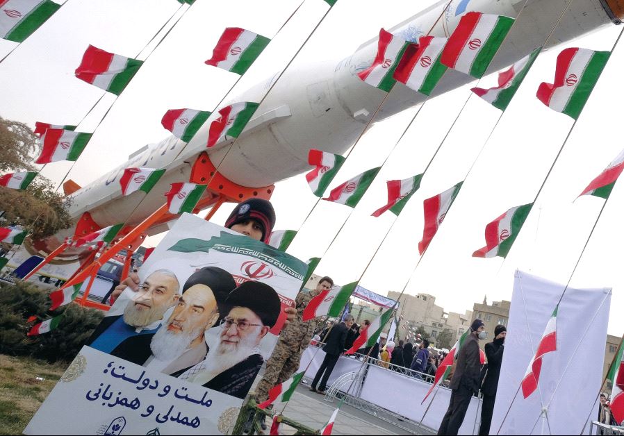 A boy holding a placard with pictures of (left to right) Iranian President Hassan Rouhani, the late founder of the Islamic Revolution Ayatollah Ruhollah Khomeini, and Iran’s Supreme Leader Ayatollah Ali Khamenei, poses in front of a model of a satellite-carrier rocket last year