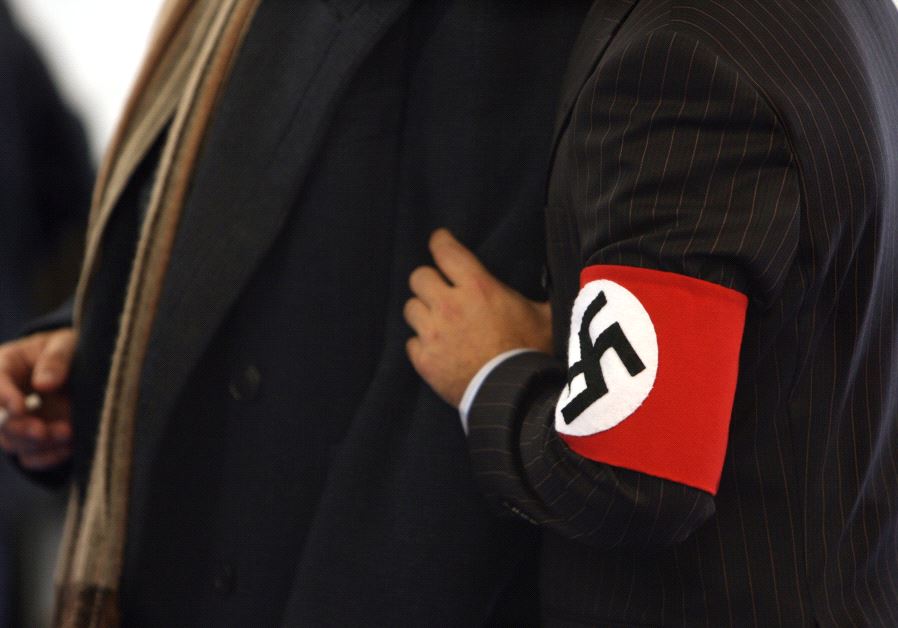 A man wears a costume with a swastika armband 