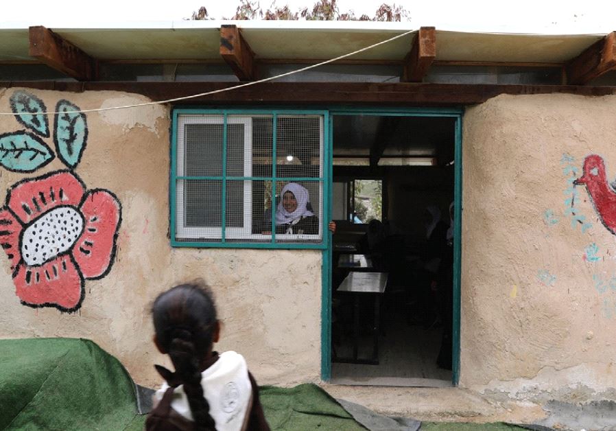A BEDUIN SCHOOLGIRL looks out the window of her classroom at the Al-Khan al-Ahmar school, near the West Bank city of Jericho.