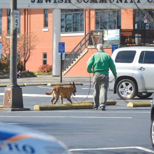 A policeman and a detection dog search for explosives after a bomb threat to the Jewish Community Center in Louisville, Kentucky