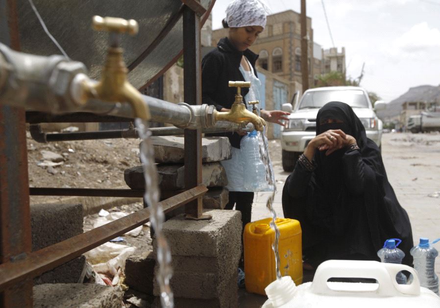 A woman fills jerrycans with clean water from a donated source amid a shortage of water supplies, in Yemen's capital Sanaa, April 14, 2016. 