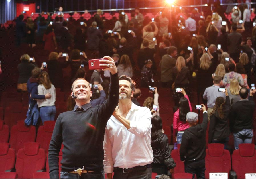TBEX participants take a group selfie as visiting American actor Corin Nemic (left) and Israeli actor Ishai Golan do the same, at the conference opening party at Cinema City