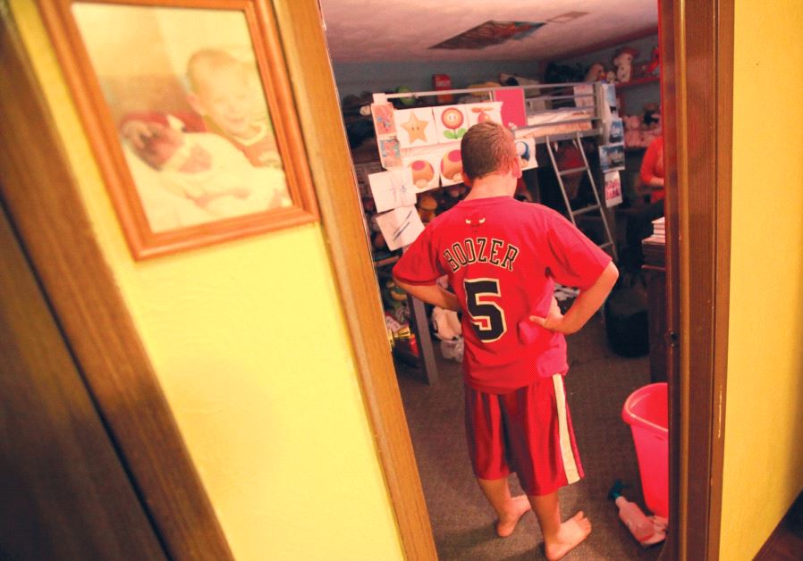 A boy with autism stands in his room
