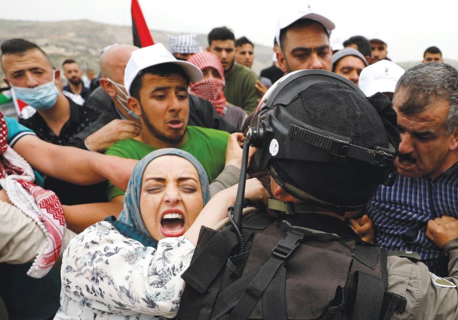 PALESTINIAN PROTESTERS clash with a soldier during a Land Day protest in Madama, south of Nablus.