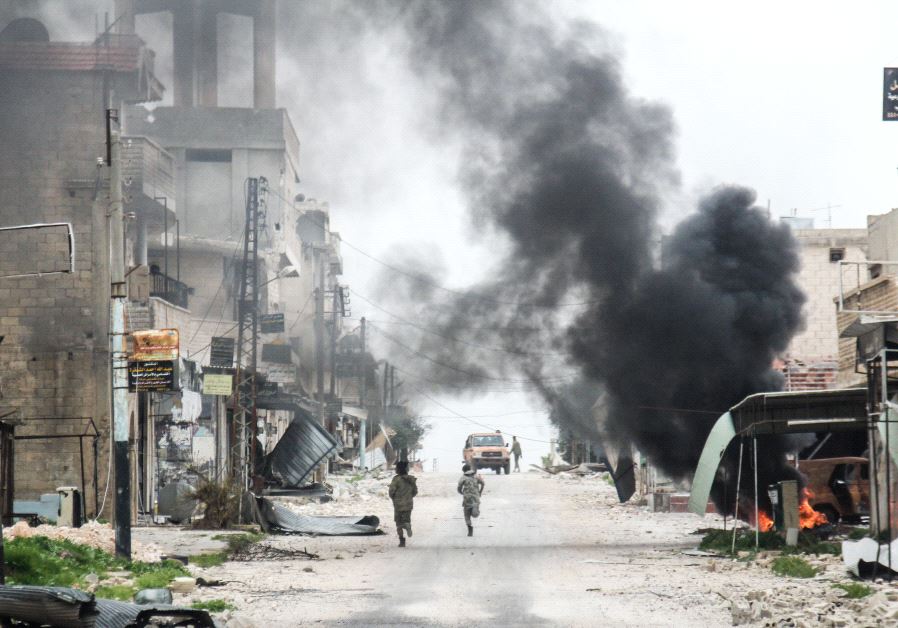 A picture taken on March 22, 2017 in the Syrian town of Tayyibat al-Imam in the countryside of the central province of Aleppo, shows fighters running amdist destruction down a street past a rising plume of smoke from a burning tire meant to disrupt warplanes