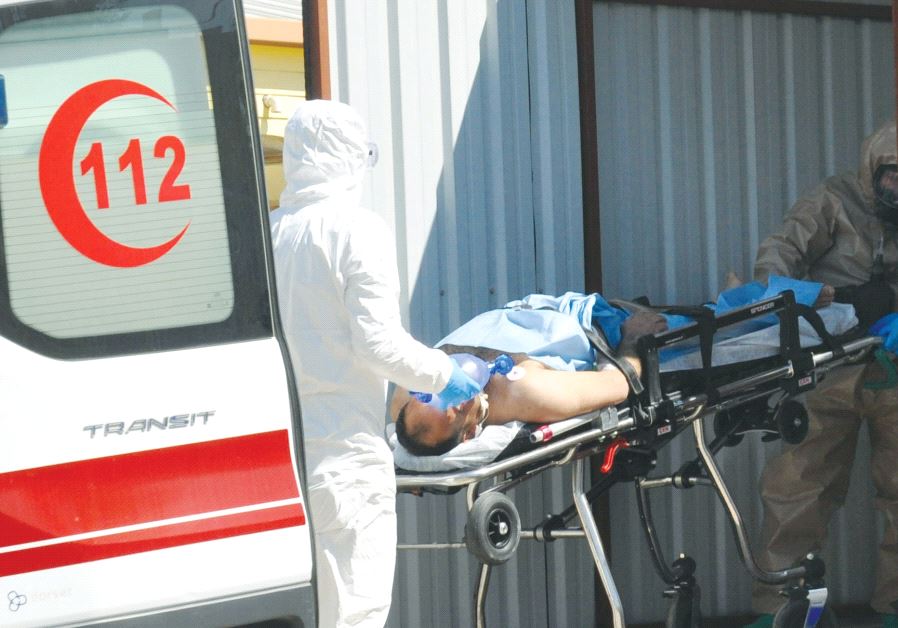 A Syrian man from Idlib is carried by Turkish medics wearing chemical protective suits to a hospital in the border town of Reyhanli in Hatay province, Turkey