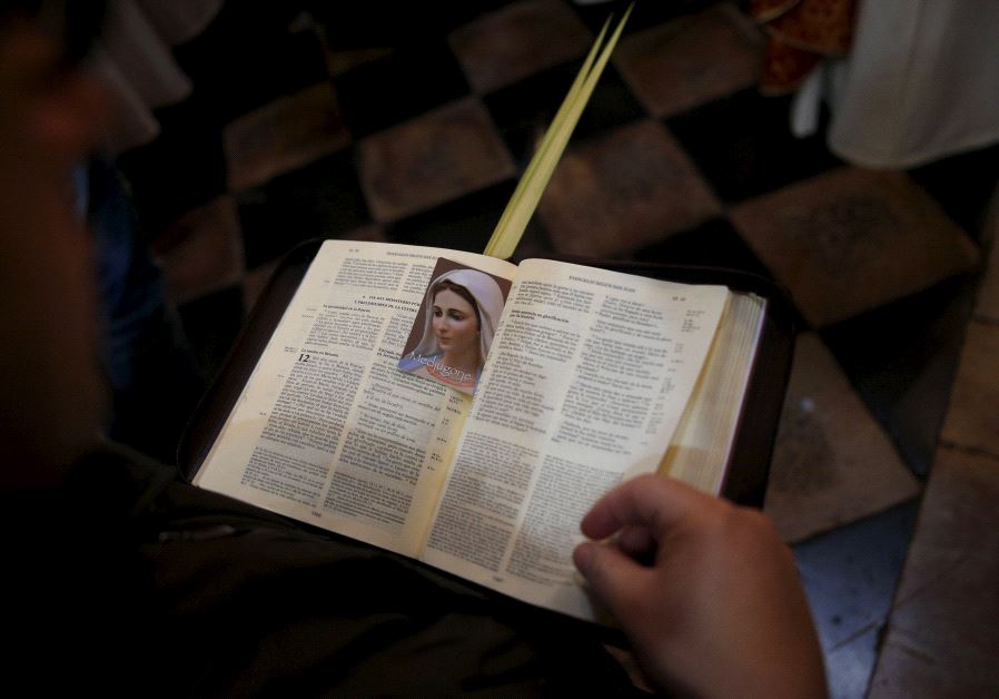 A worshipper holds an opened Bible during a Palm Sunday procession at the Church of the Holy Sepulchre in Jerusalem's Old City.