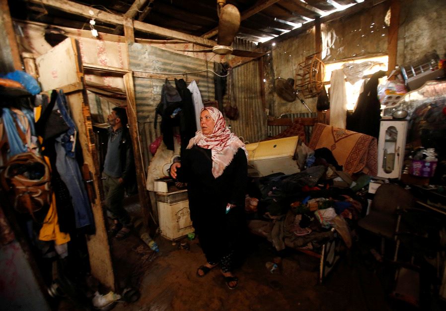 A Palestinian woman inspects her shelter that was flooded during a rainstorm, in the northern Gaza Strip.