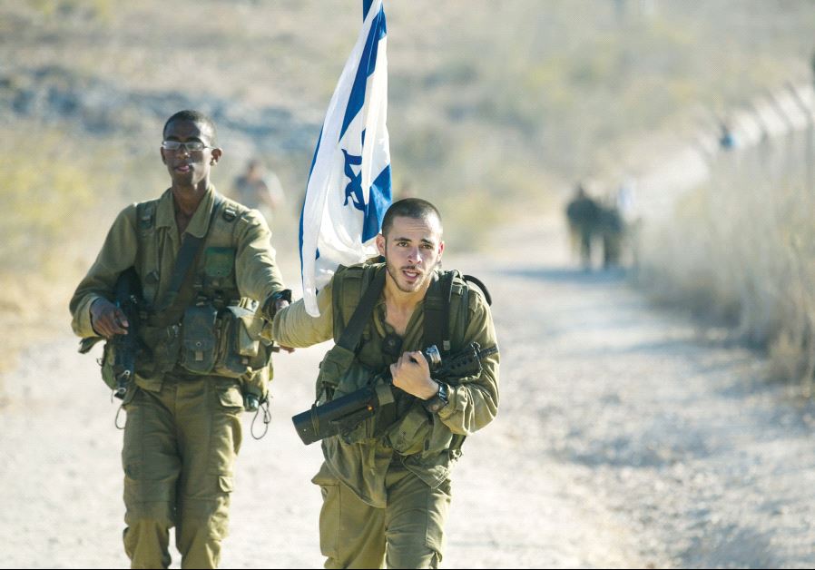 A soldier from the Golani Brigade holds a comrade’s hand as he helps him during a 70-kilometre march, marking the completion of their advanced training, at the end of which they receive their brown beret, in 2014