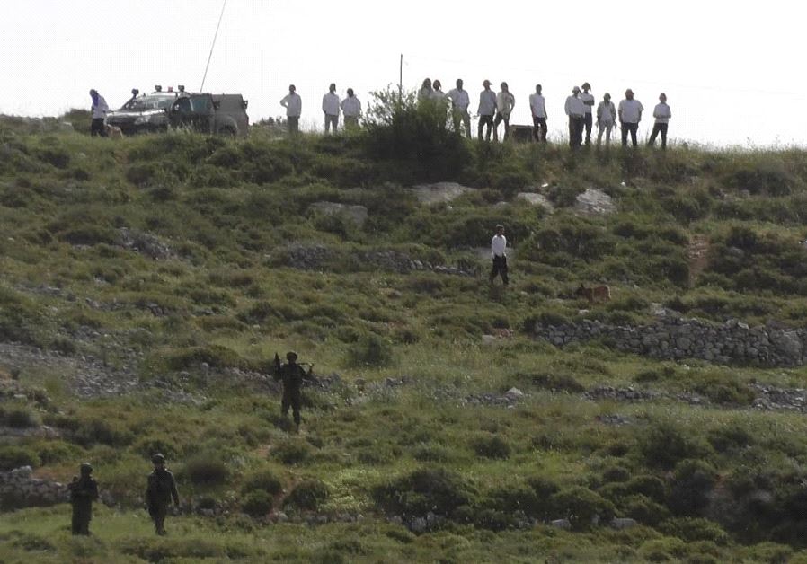 Settlers and IDF soldiers stand on a hilltop outside the Yitzhar settlement