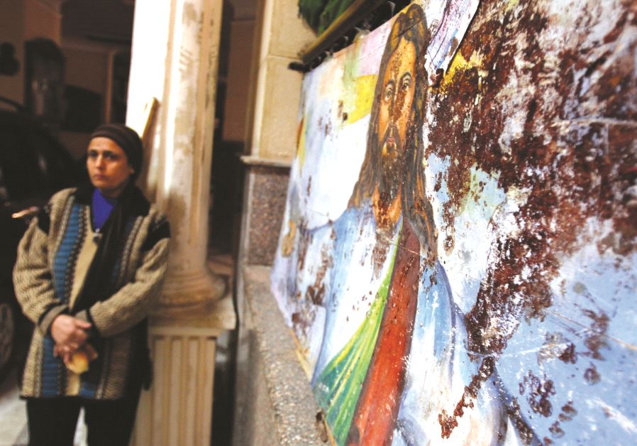 Une femme près d'une peinture du Christ, tâchée de sang lors d'un attentat dans une église copte