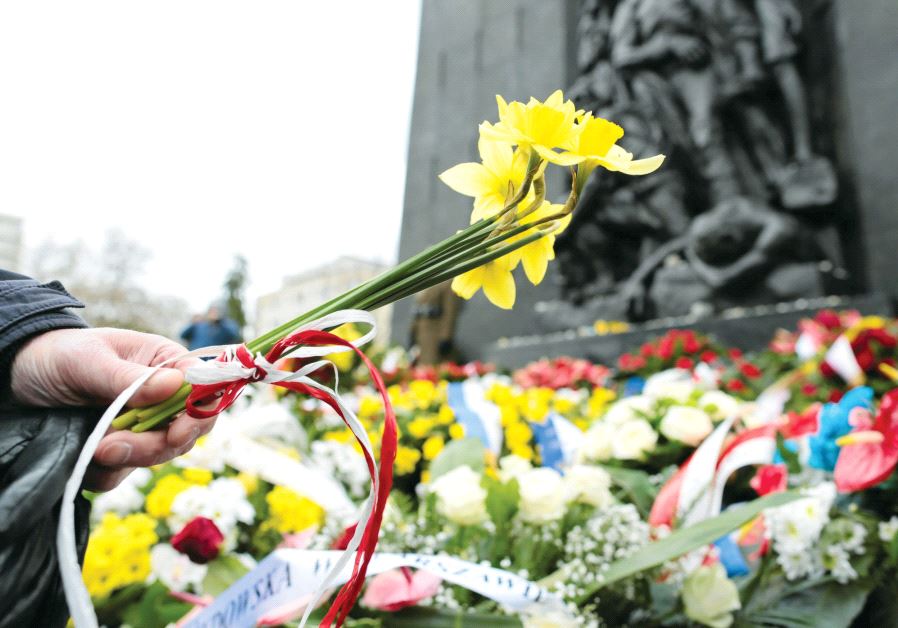 A man lays daffodils near the Ghetto Heroes monument in Warsaw