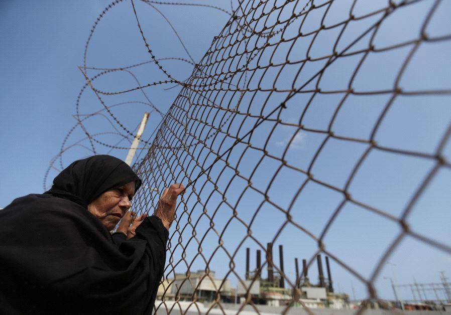 A Palestinian woman stands by a fence during a protest calling for an end to the power crisis, outside the power plant in the central Gaza Strip April 23, 2017.