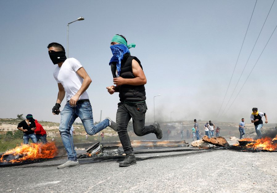 Palestinian protesters run during clashes with Israeli troops at a protest in support of Palestinian prisoners on hunger strike in Israeli jails.