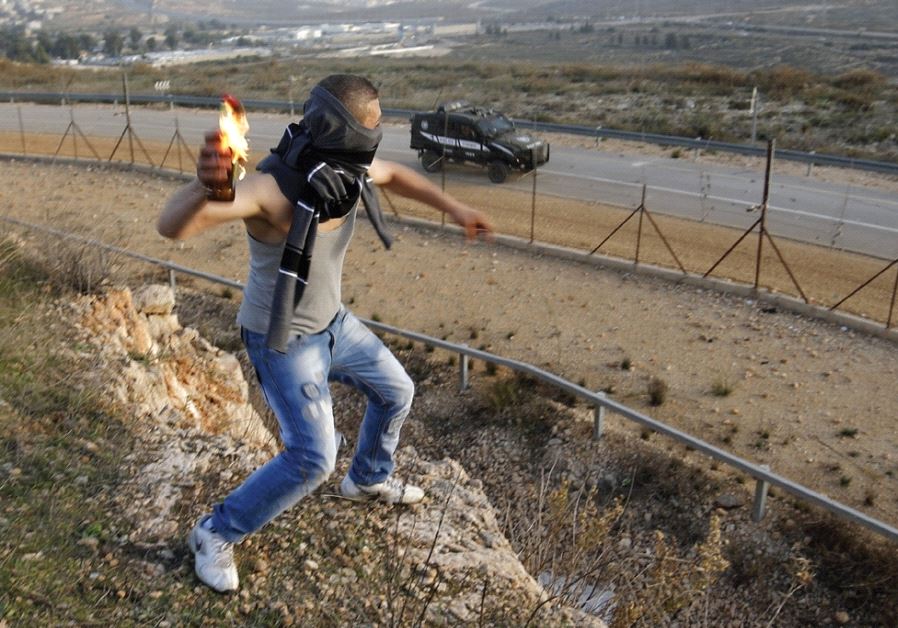 WHO IS paying him? A Palestinian throws a molotov cocktail at an Israeli jeep